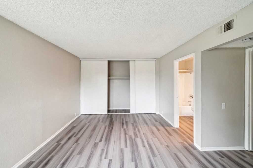 the spacious living room of an apartment with wood flooring