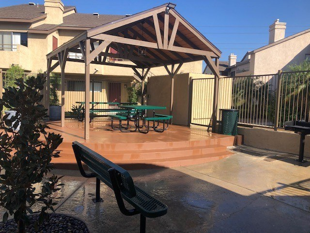 a patio with a bench and table in front of a house