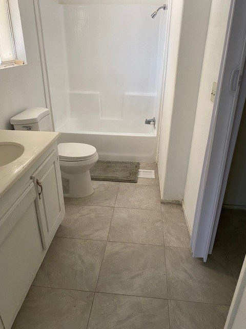 A white toilet is in a bathroom with a tiled floor.