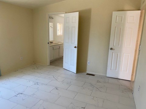 A room with a marble floor and two white doors.