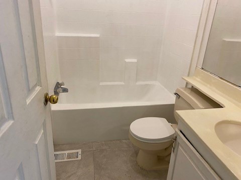 A white toilet sits next to a bathtub in a bathroom.