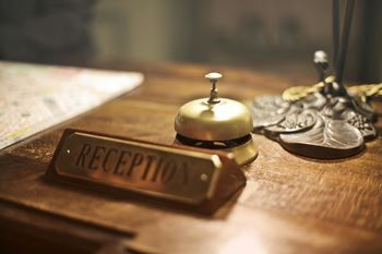 A reception desk with a gold bell and a sign reading "RECEPTION".