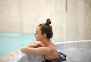 A person with a bun hairstyle is sitting in a hot tub.
