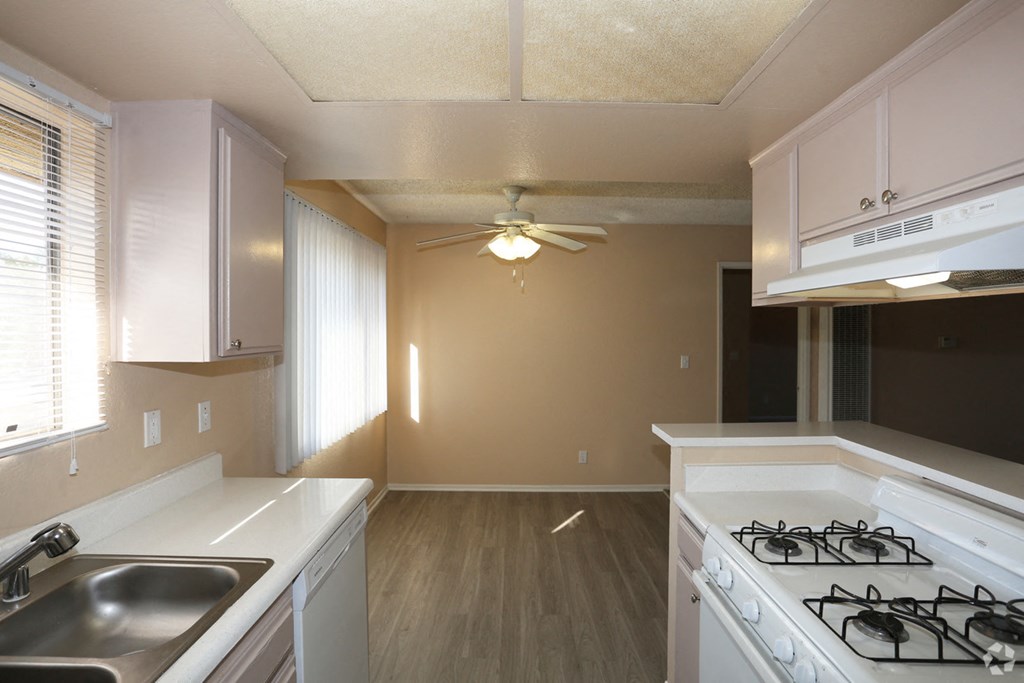 an empty kitchen with a stove and a ceiling fan
