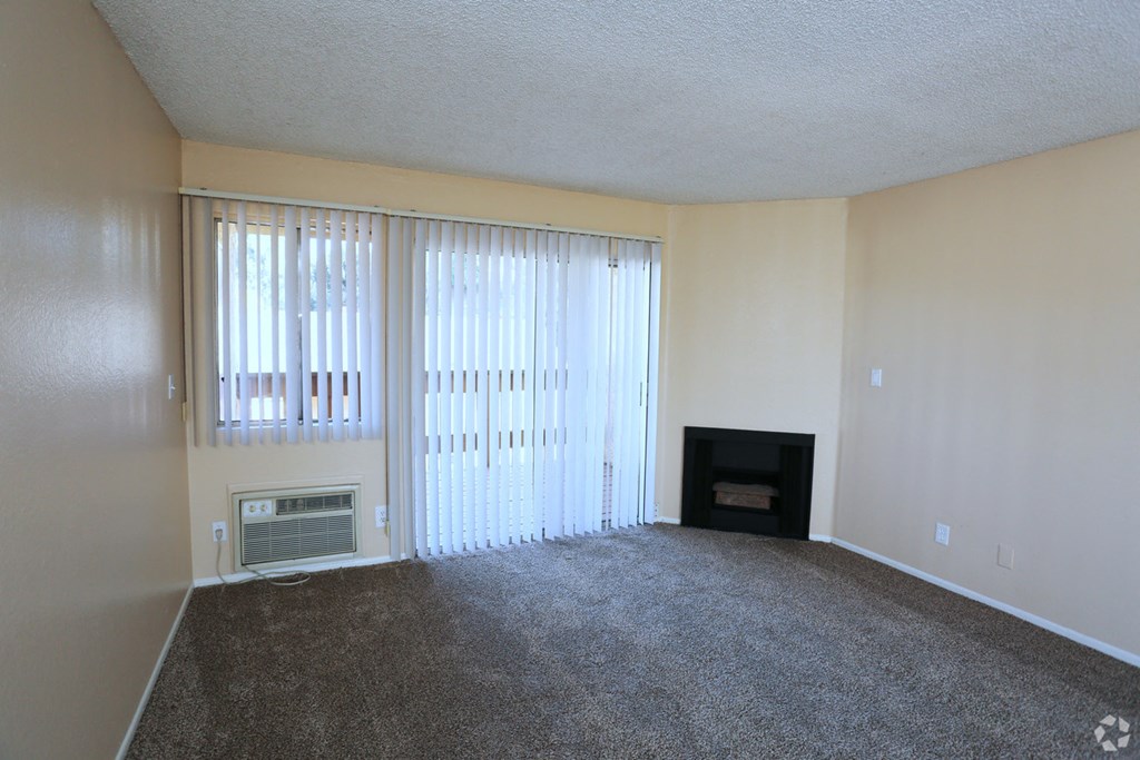 an empty living room with a fireplace and windows