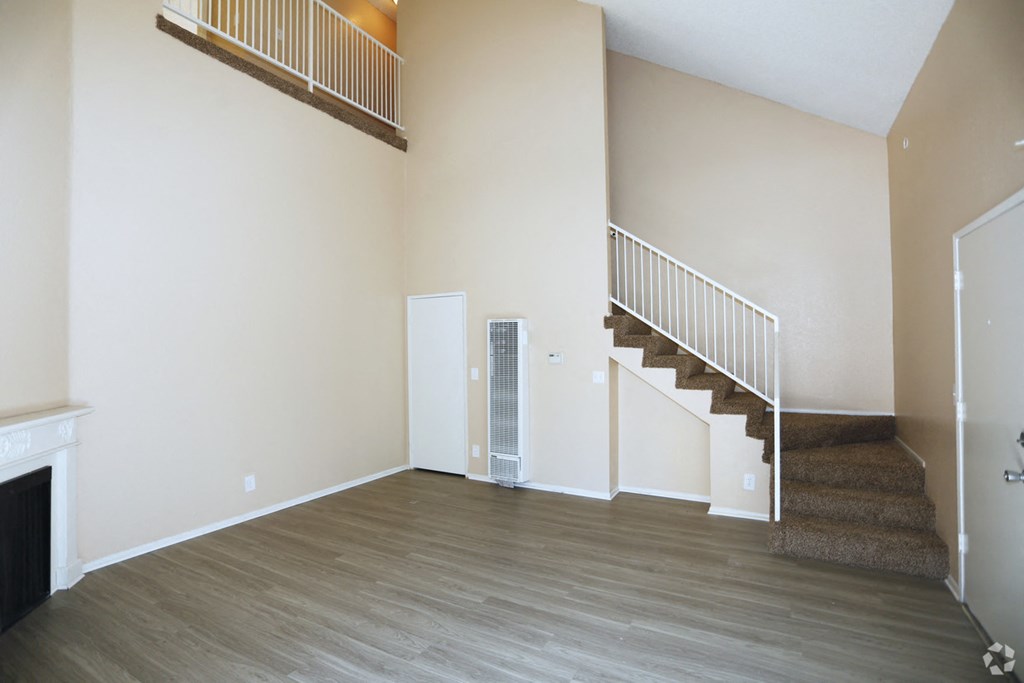 an empty living room with wood floors and a staircase