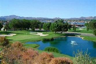 A golf course with a pond and trees in the foreground.