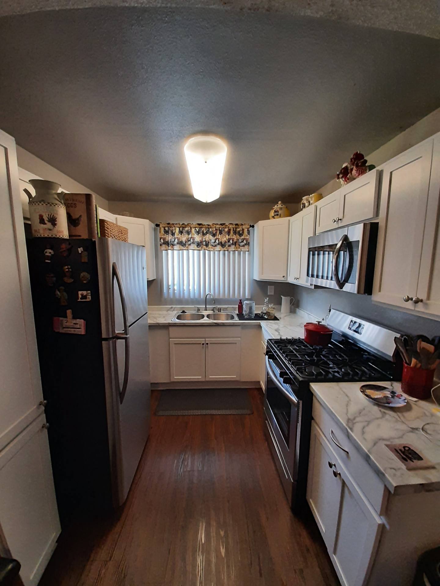 a small kitchen with white cabinets and a black refrigerator