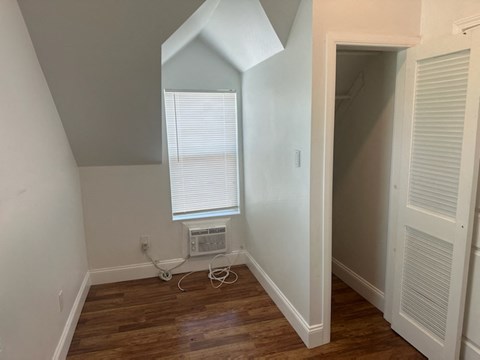 a room with a window and a wooden floor and an air conditioner
