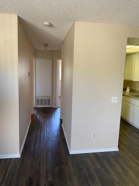 A long hallway with wood floors and white walls.