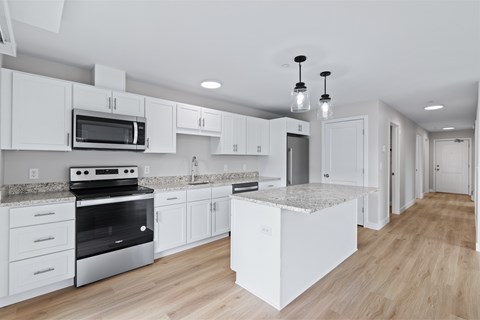 A modern kitchen with white cabinets and a marble island.