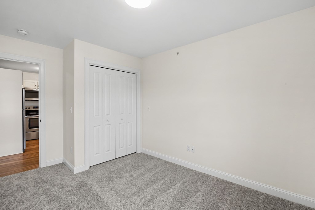a bedroom with white walls and a door to a closet