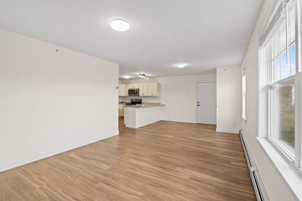 a living room and kitchen with wood floors and white walls