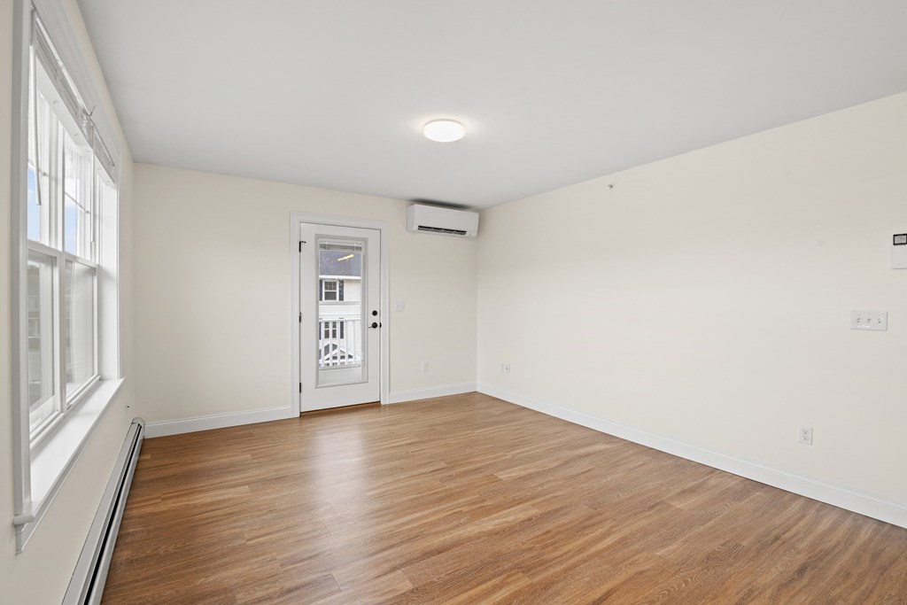 a living room with white walls and wood floors and a white door
