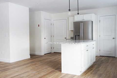 A kitchen with white cabinets and a wooden floor.
