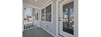 A white door is open to a deck with a railing.