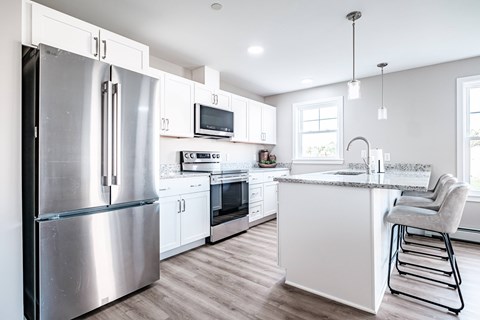 A modern kitchen with a stainless steel refrigerator and white cabinets.
