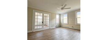A room with a ceiling fan and a door leading outside.