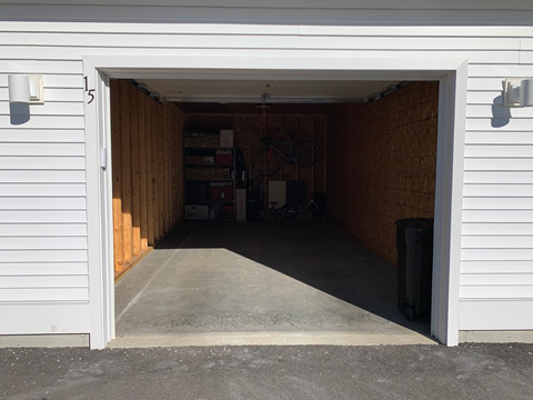 A white garage door is open to reveal a dark interior.