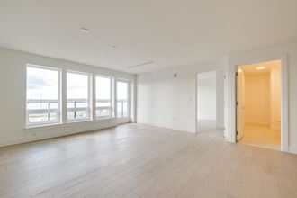 an empty living room with large windows and wood flooring