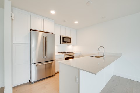a large white kitchen with stainless steel appliances and a white counter top