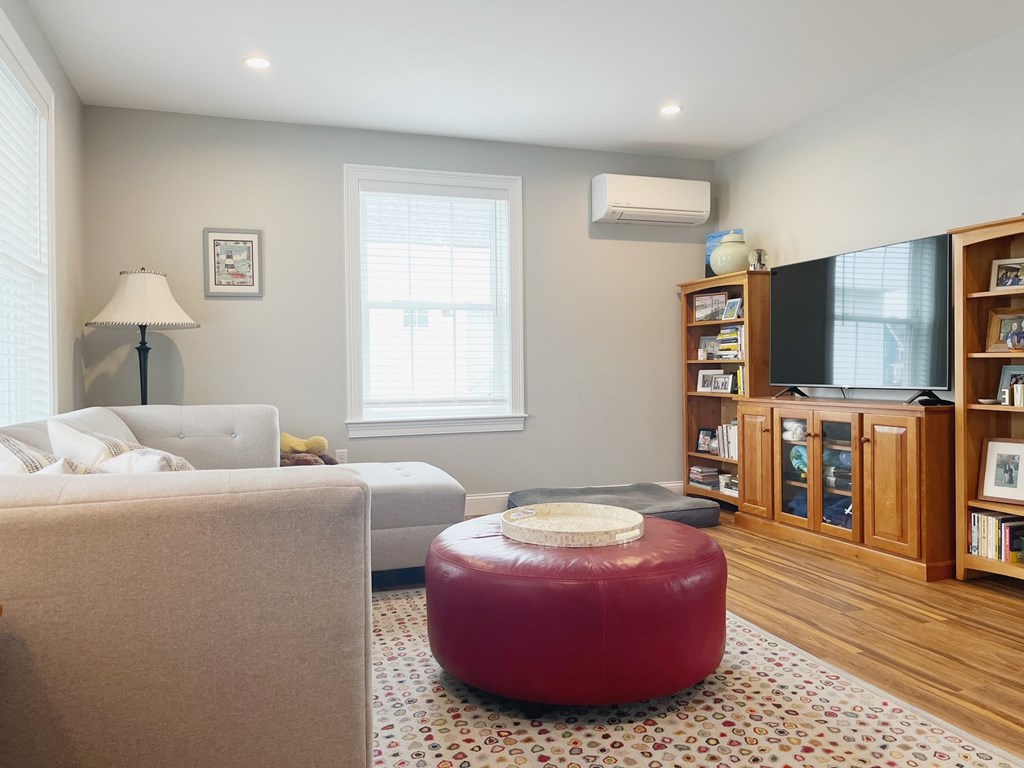 A living room with a red ottoman and a grey sofa.