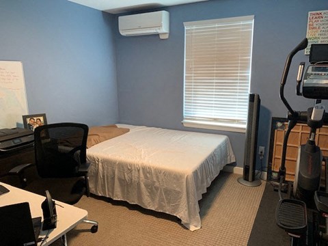 A room with a bed, desk, and exercise equipment.