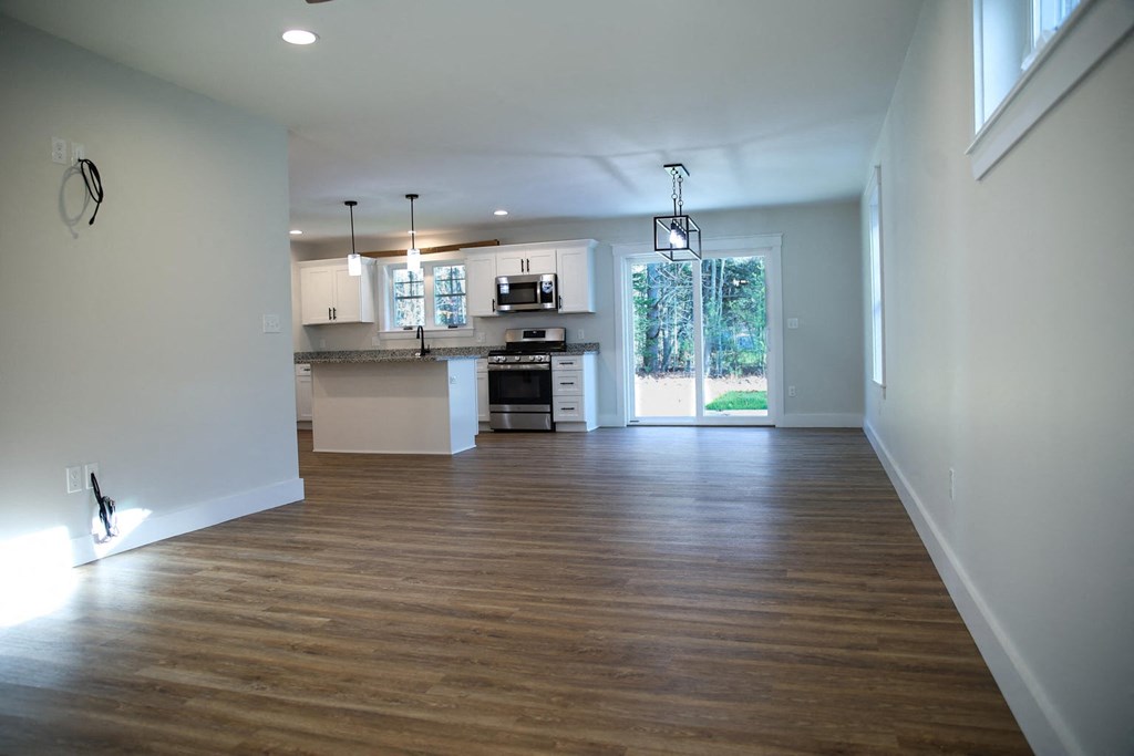 an empty living room and kitchen with wood floors