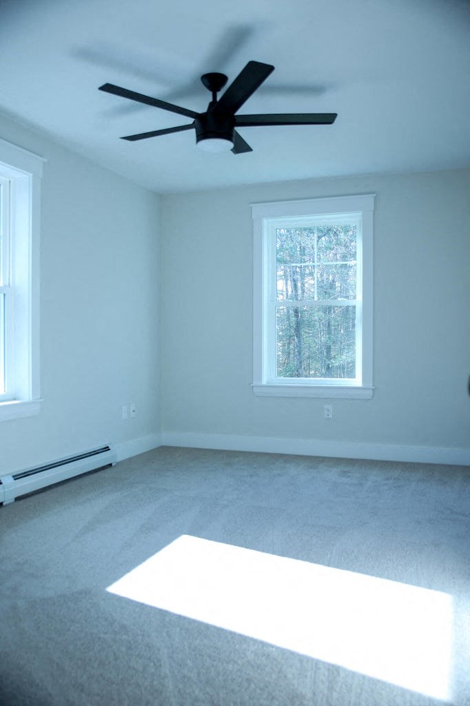 an empty room with a ceiling fan and two windows