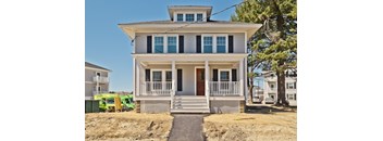 A two-story house with a front porch and a brown door.