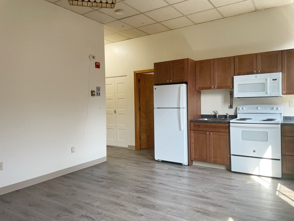 an empty kitchen with white appliances and wooden cabinets