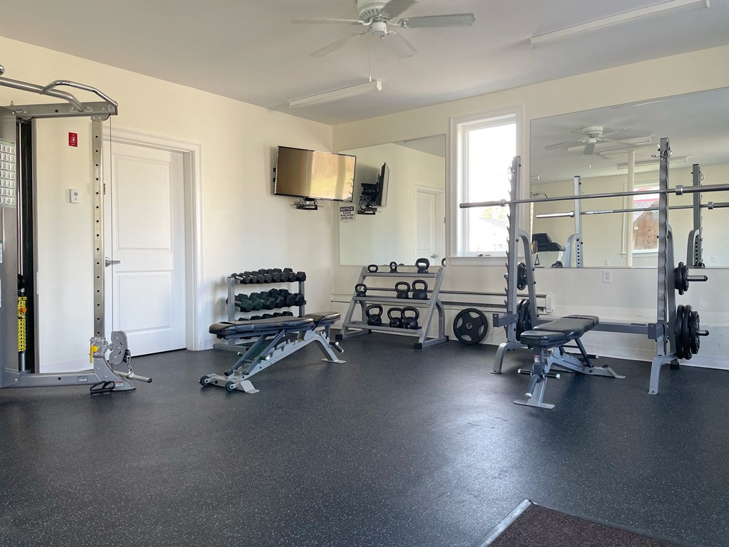 a fitness room with weights and a tv