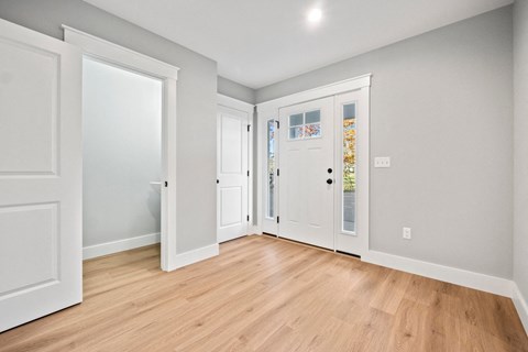 a living room with white doors and a wood floor