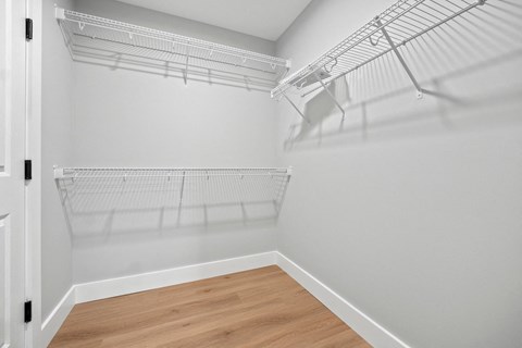 the closet in a bedroom of a house with white walls and wood floors