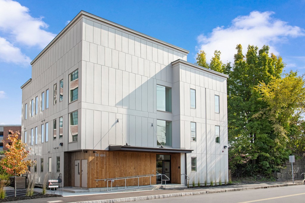the exterior of a white building with a wooden facade
