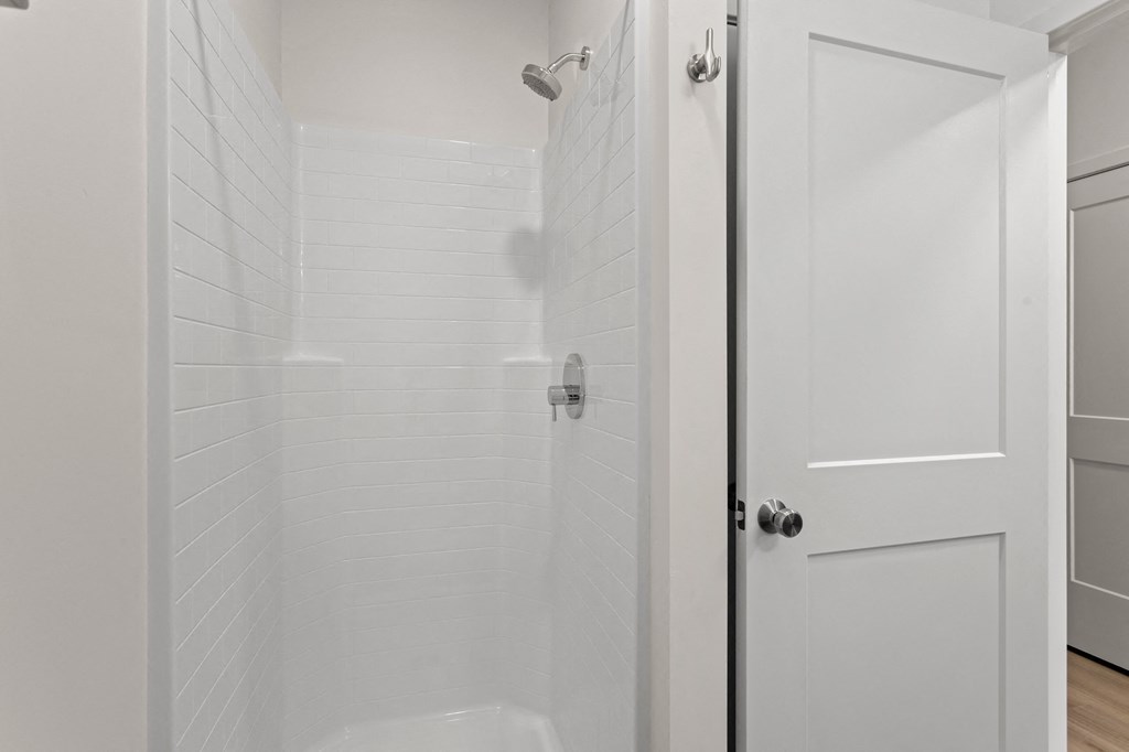 a bathroom with a shower and a white door
