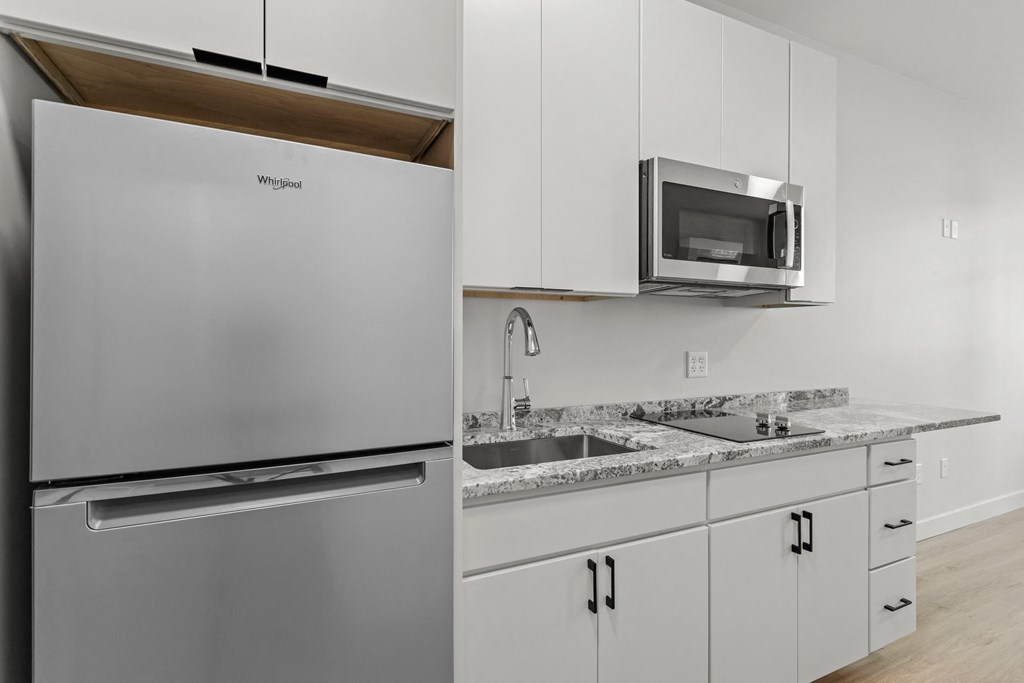 a kitchen with white cabinets and a stainless steel refrigerator and sink