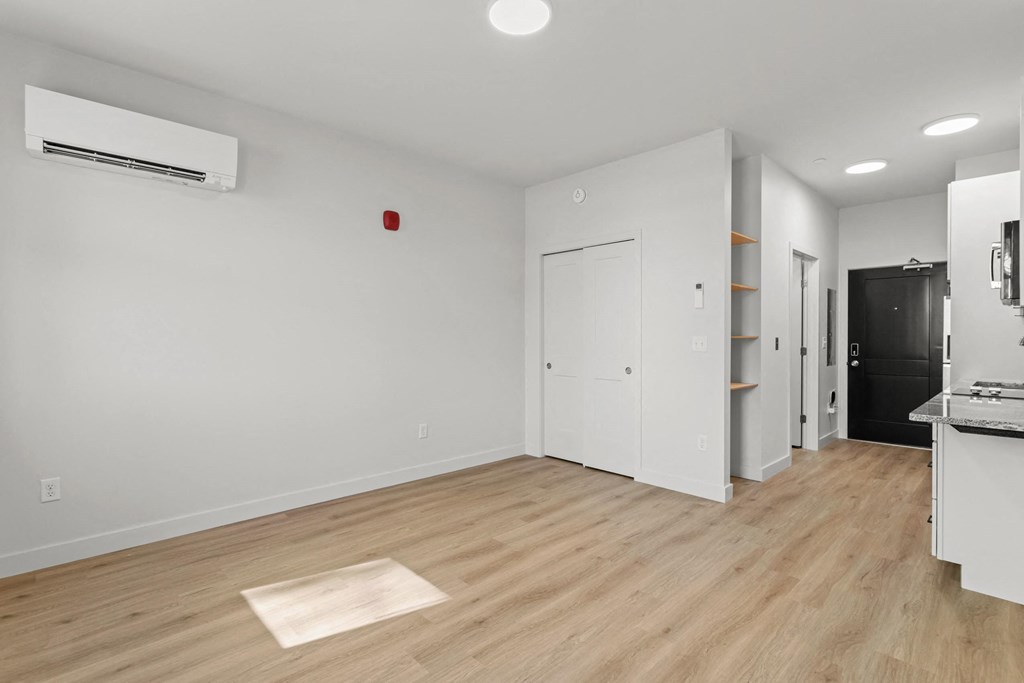 a living room and kitchen with white walls and wood floors