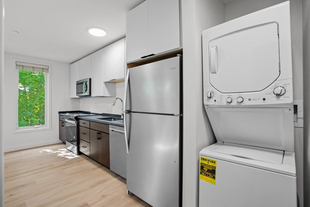 a white kitchen with a washer and dryer and a window