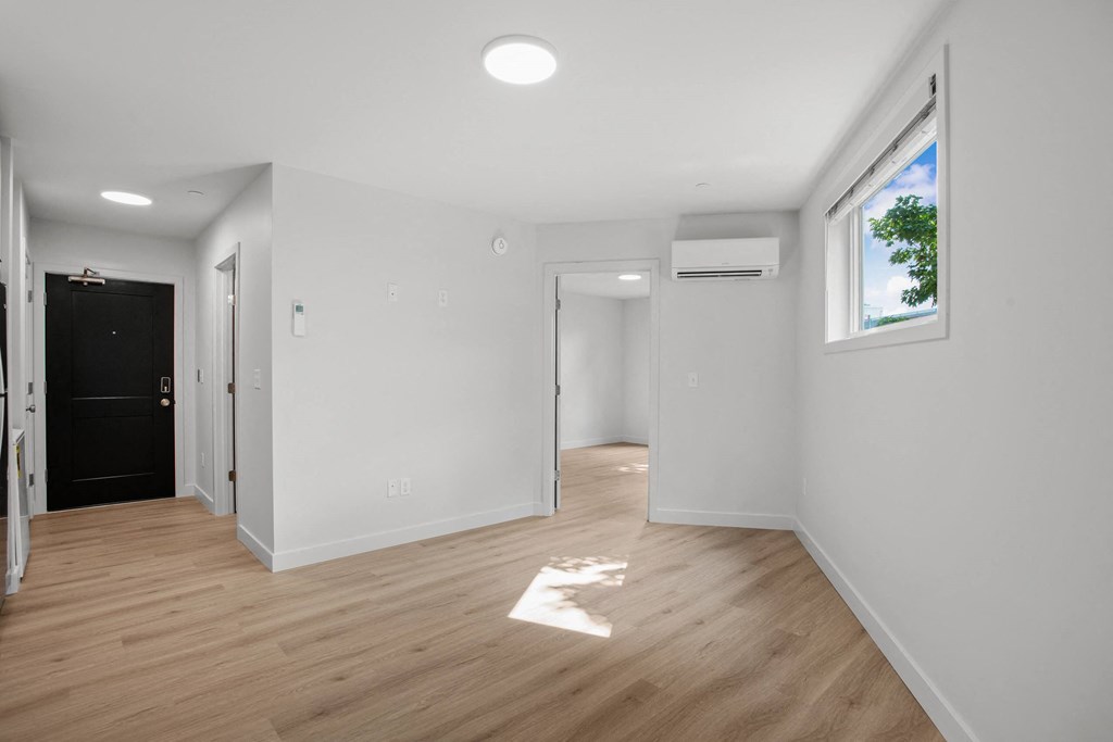a living room with white walls and a window and wooden floors