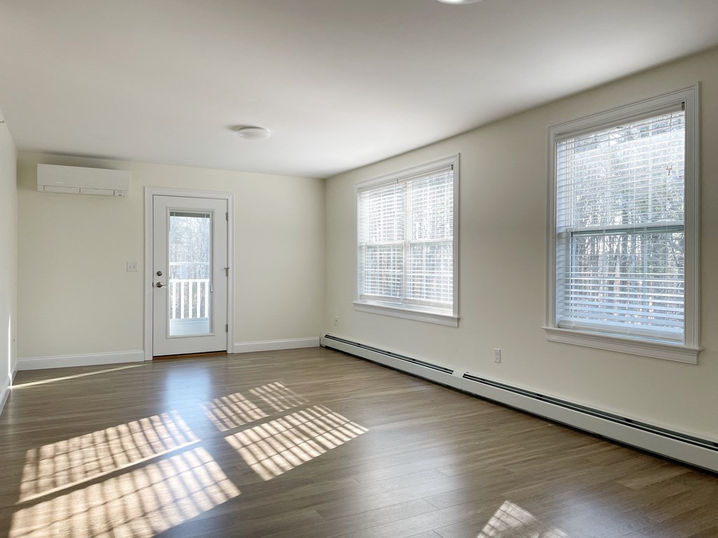an empty living room with wood flooring and two windows