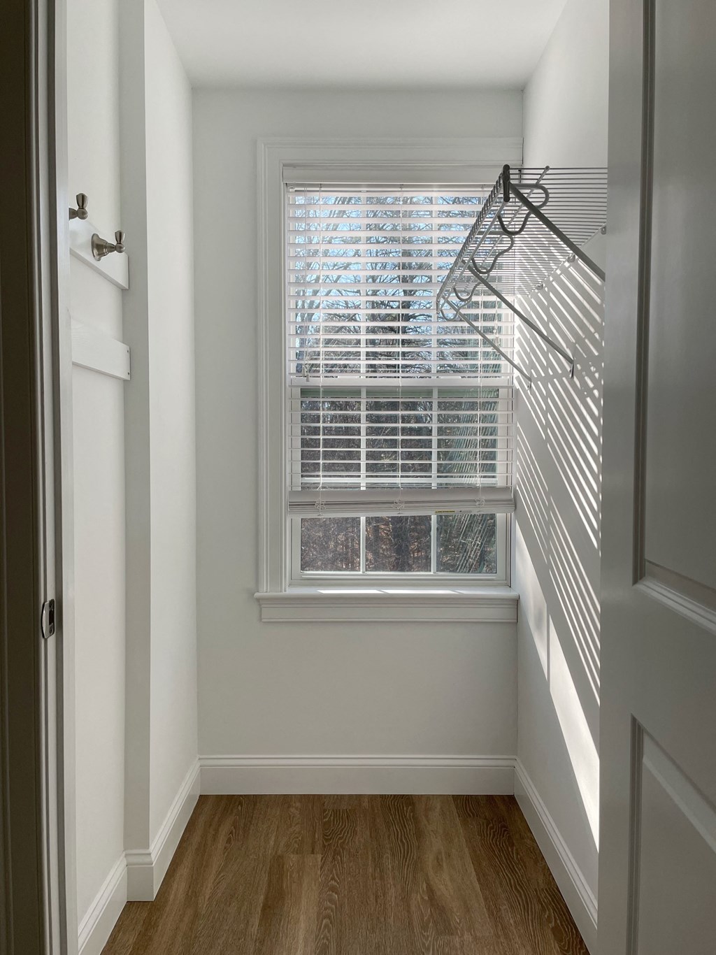 a room with a window and a closet with a hanger on the wall