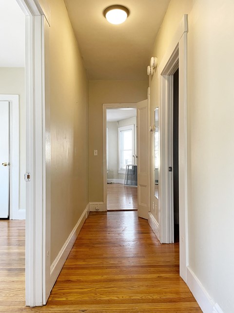 an empty hallway with wood flooring and white walls