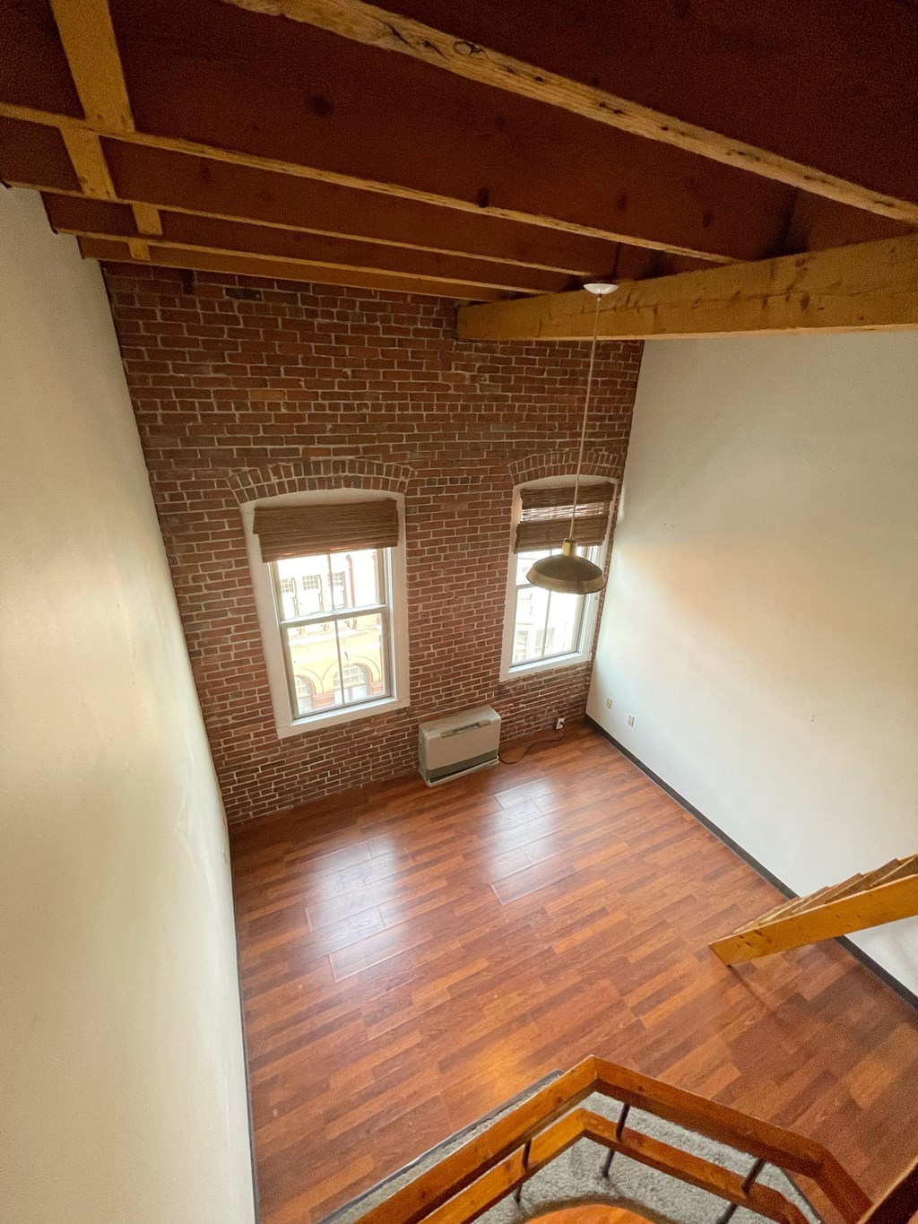 an empty living room with a brick wall and wooden floors