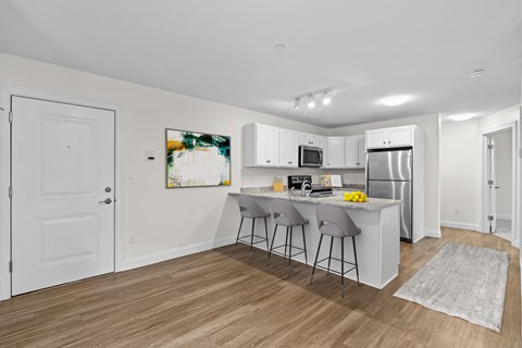 a kitchen with white cabinets and a island with two stools