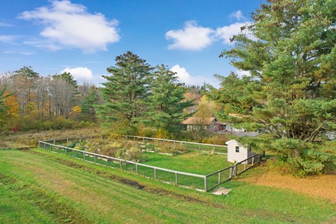 a farm with a fence and a small white house in a field