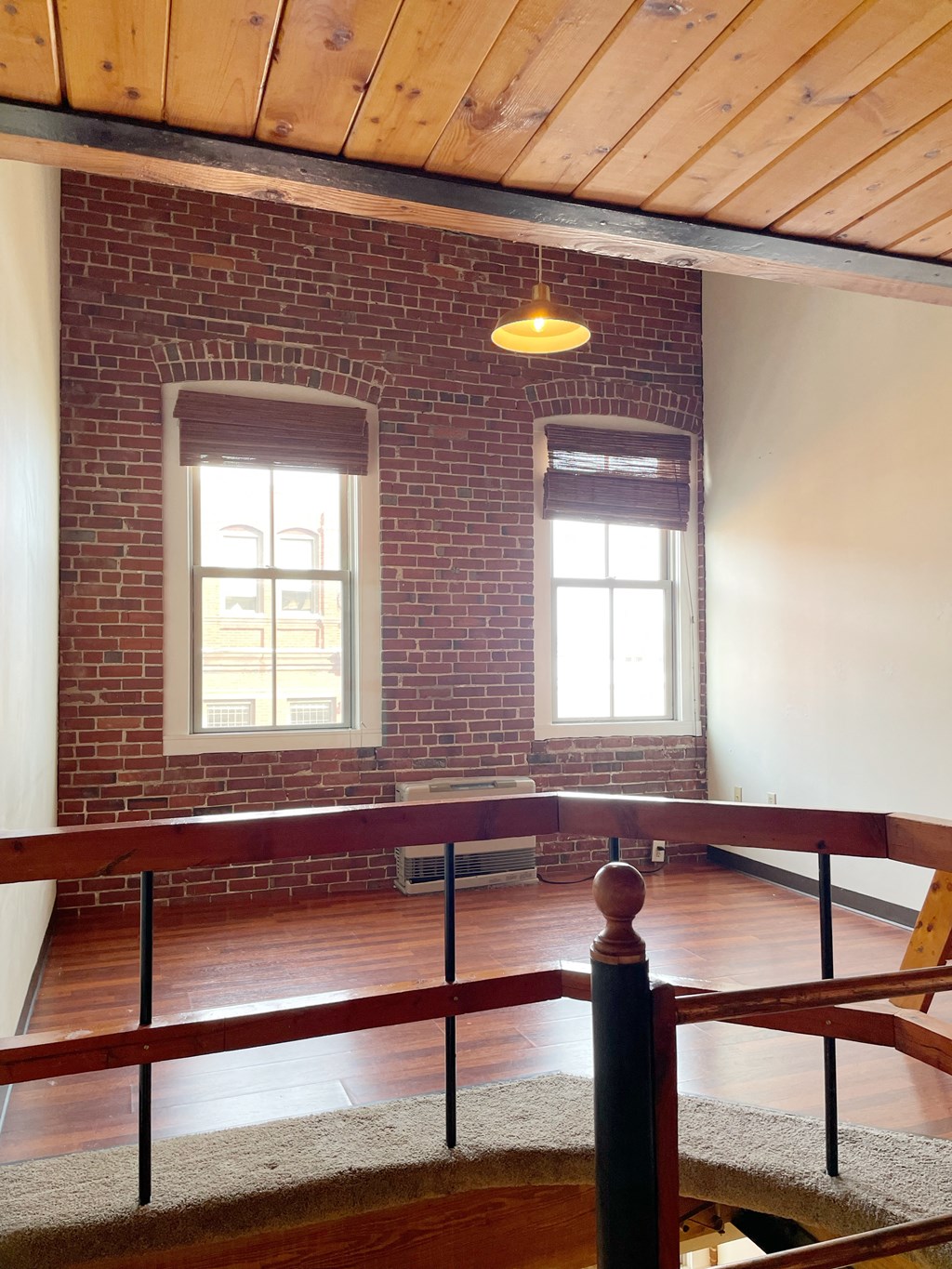 an empty room with a brick wall and a wooden railing