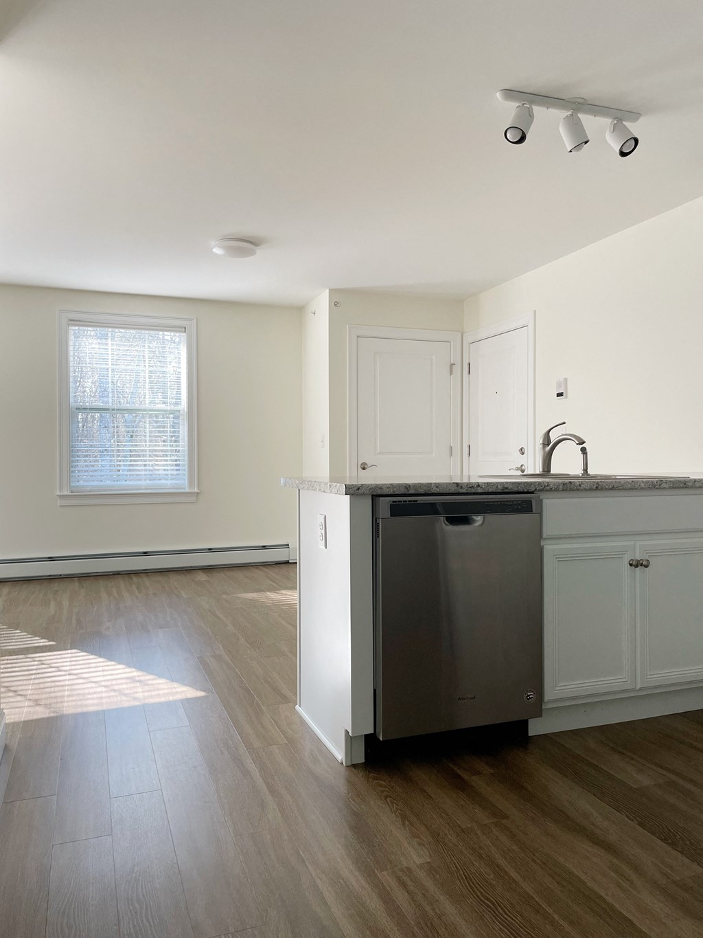 an empty kitchen with white cabinets and a stainless steel dishwasher