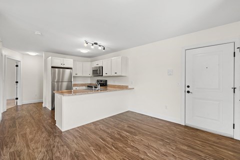 A kitchen with white cabinets and a wooden floor.