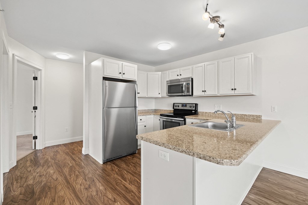 a kitchen with a granite counter top and a stainless steel refrigerator